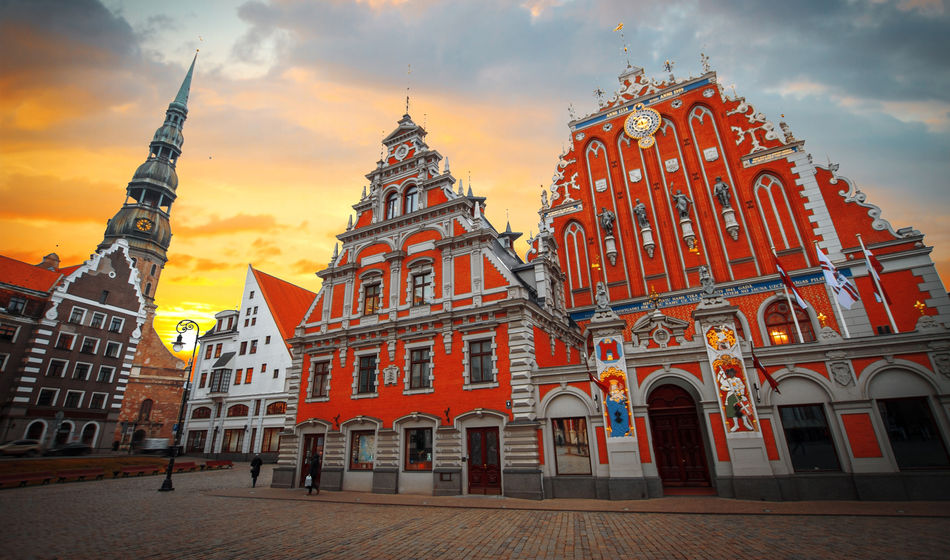 City Hall Square with House of the Blackheads and Saint Peter church in Old Town of Riga in the evening, Latvia (photo via Lindrik / iStock / Getty Images Plus)