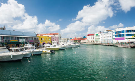 Main water canal with ships and shops in Bridgetown, capital of Barbados. Caribbean (photo via Fyletto / iStock / Getty Images Plus)