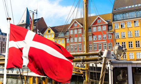 Denmark&#39;s national flag flying in the foreground of Copenhagen&#39;s famous old Nyhavn port.