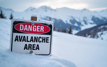 Avalanche danger area sign in a snowy mountain landscape.