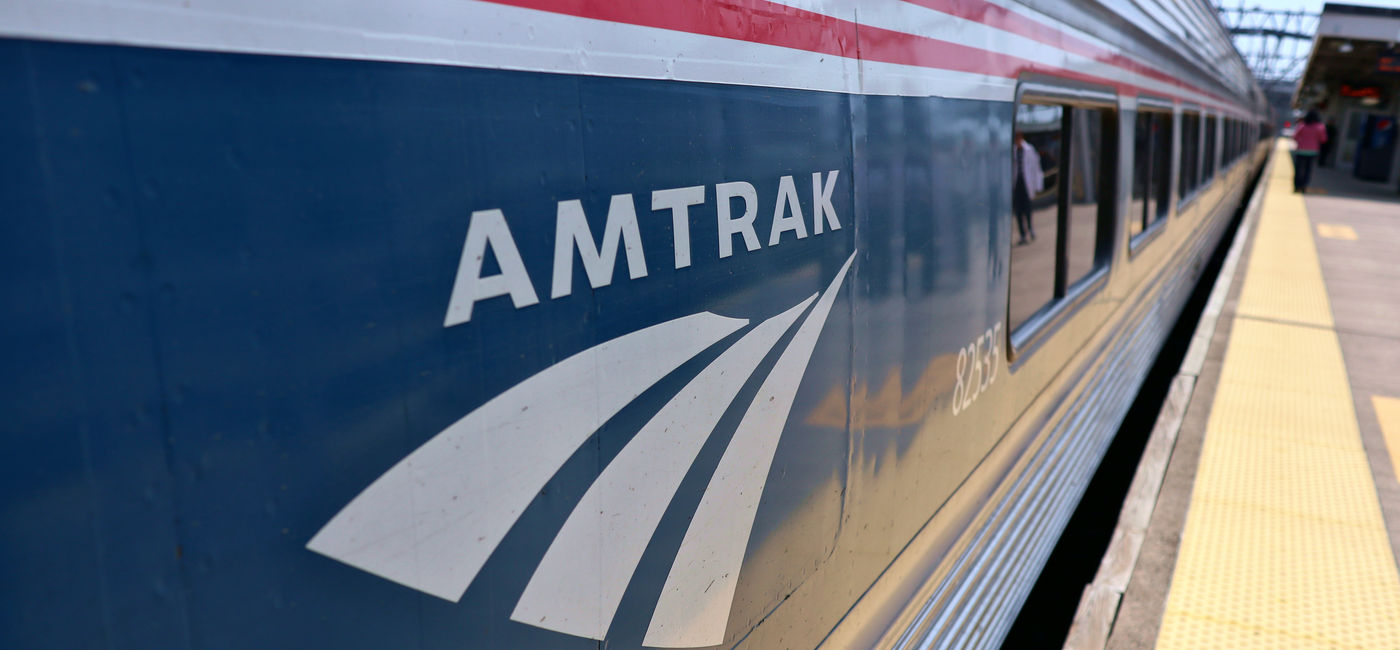 Image: Amtrak logo on the side of a train. (Photo Credit: Yuriy T / Adobe Stock)