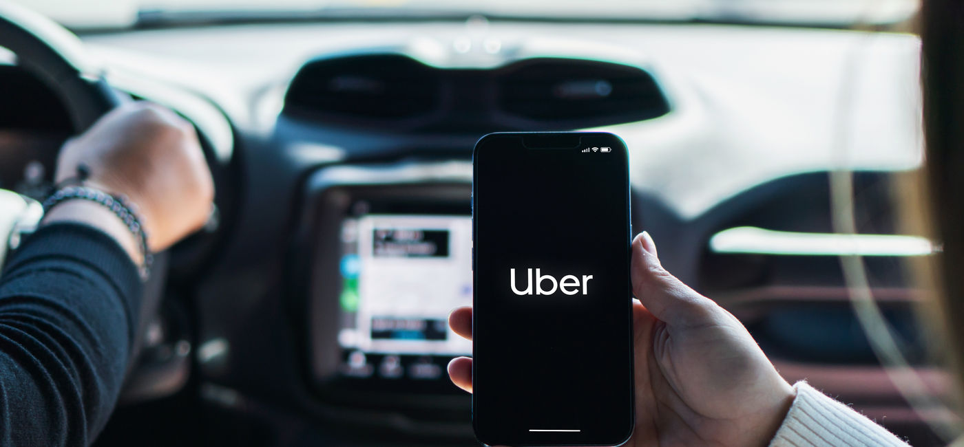 Image: Car passenger using the Uber app on her mobile phone. (Photo Credit: Adobe Stock/Diego)