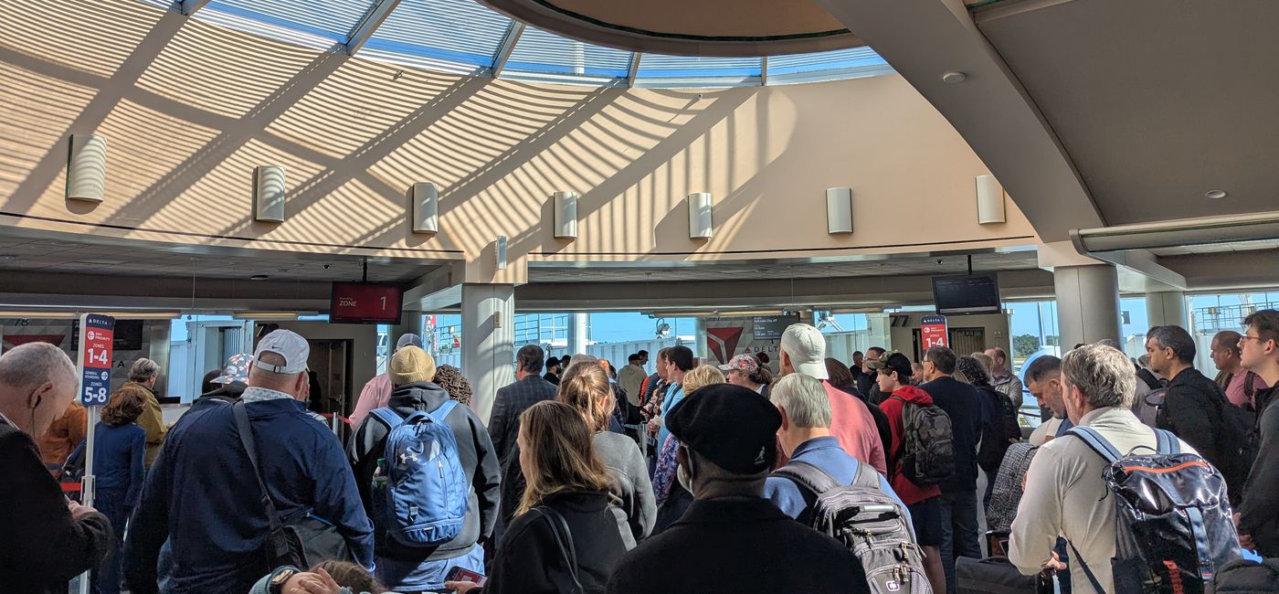 Image: Travelers crowd together before boarding airplane (Photo Credit: Eric Bowman)