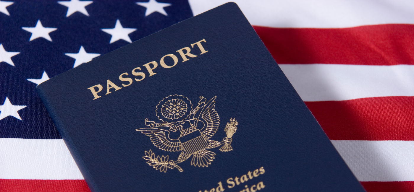 Image: U.S. passport sitting atop an American flag. (Photo Credit: Adobe Stock/InterestingClip)