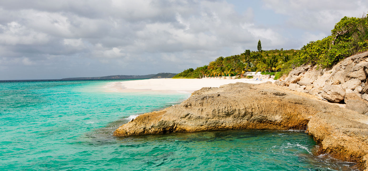 Image: view at rugged rocky seashore and white sand empty beach at anguilla, island in caribbean sea (Photo via noblige / iStock / Getty Images Plus)