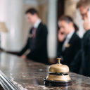 Hotel staff working at reception counter with service bell.  