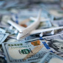 A toy airplane sitting atop a pile of US cash.